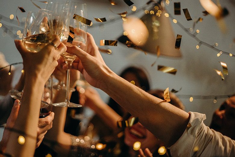 group toasting champagne gold glitter dropping from ceiling